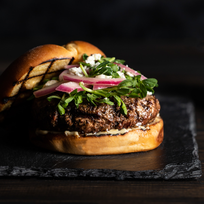Hamburger with blue cheese crumbles, red onion, and leafy greens.